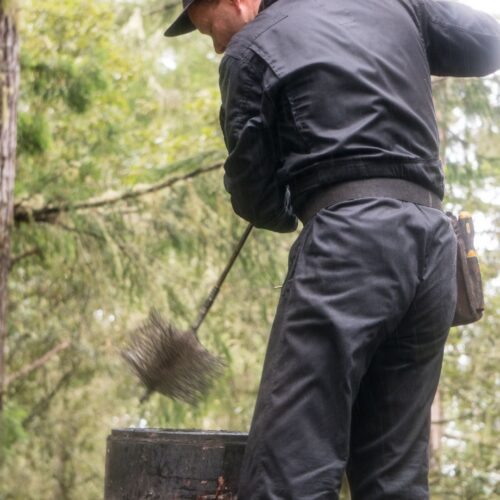 man cleaning chimney in forest