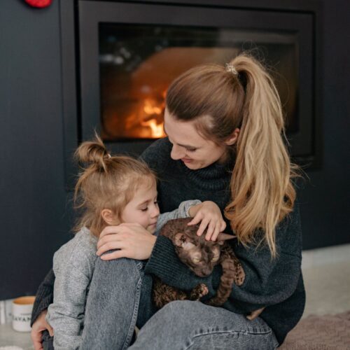 Mother and daughter cuddling by the fireplace