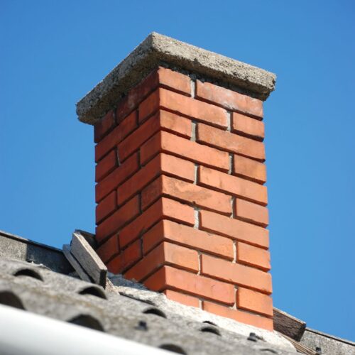 Red brick chimney against a blue sky