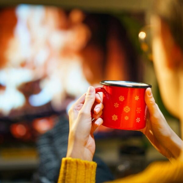 woman drinking cup of coffee by fireplace