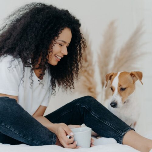 smiling woman with her dog on a bed