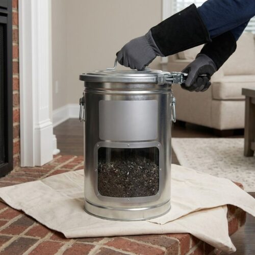 A close-up, functional photograph illustrating an industrial-grade, sealed metal containment canister filled with captured creosote debris, featuring a 'Chimney Care Plus' logo sticker, resting safely on a protective drop cloth on a residential hearth.