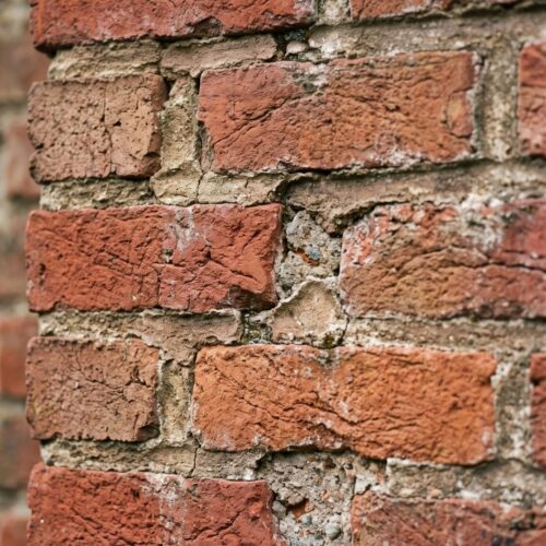 A close-up view highlighting subtle weathering and small cracks in exterior brickwork masonry.