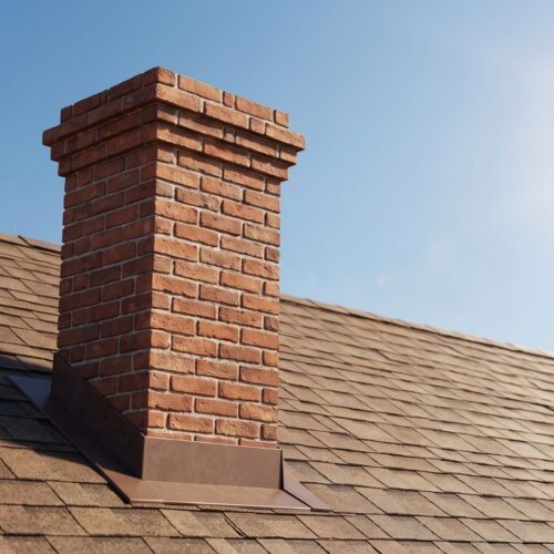 A detailed close-up showing professional metal flashing installed securely at the base of a brick chimney.